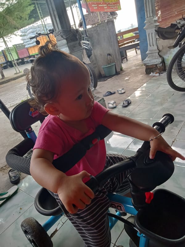 Child rides blue tricycle in Bungur, Indonesia