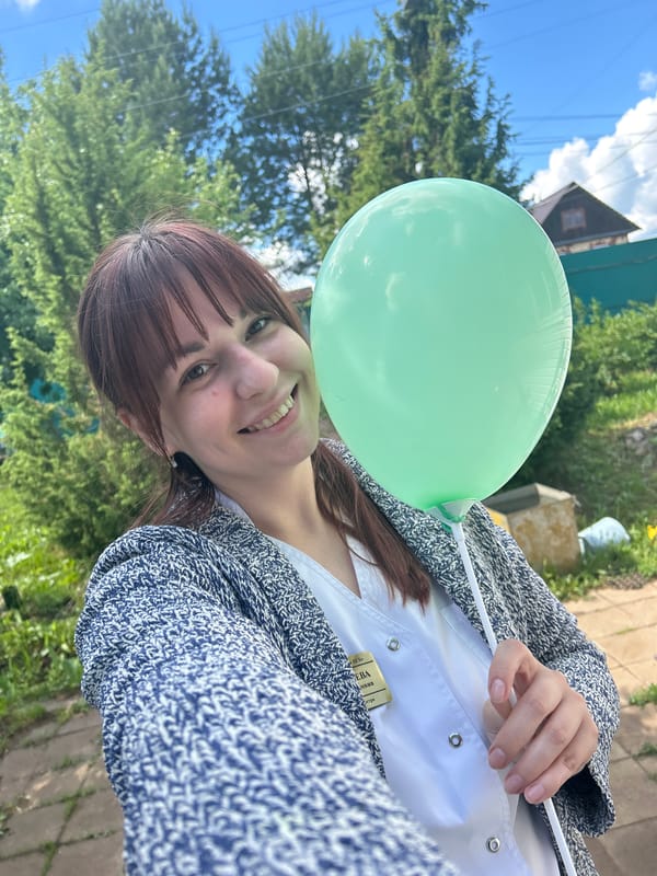 Woman holds green balloon outdoors in Russian town