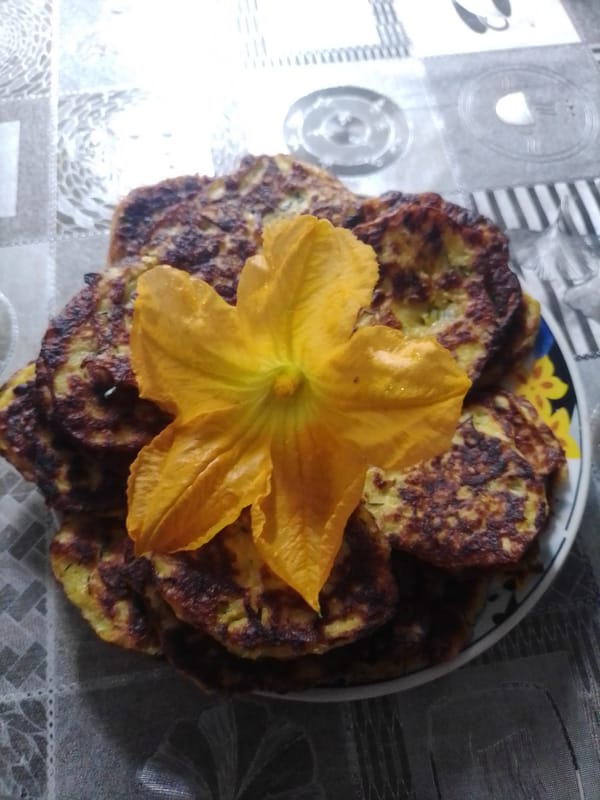 Homemade zucchini fritters from scratch, garden roses nearby.