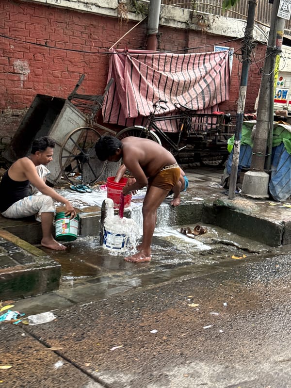 Two men bathe on street in Kolkata alleyway