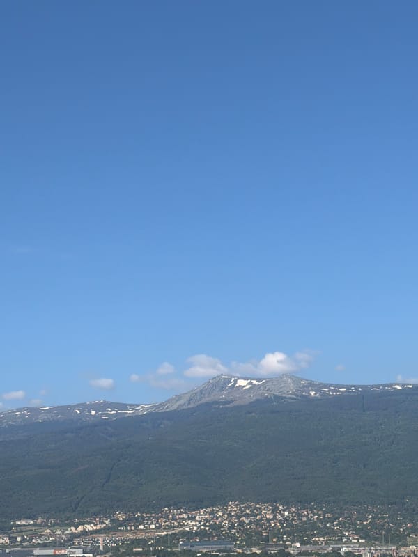 Morning view captures Sofia cityscape against snowy mountain backdrop