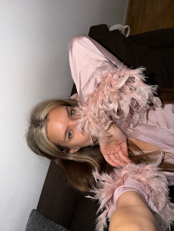 Woman in pink robe rests on couch in Berlin home