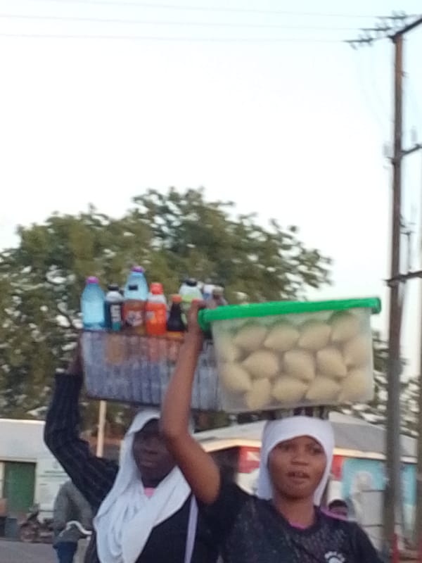 Women carry goods on heads in Tamale street scene