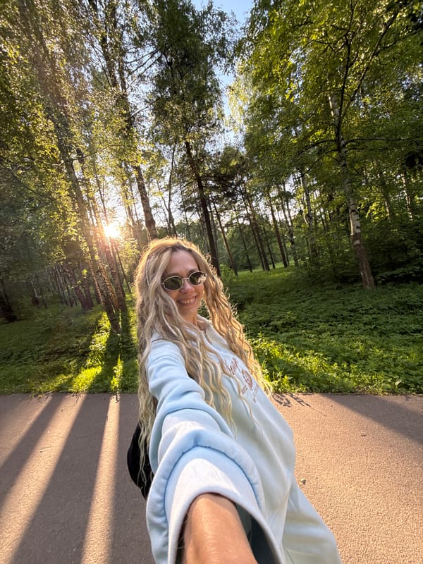 Woman takes selfie on sunny park path in Russia