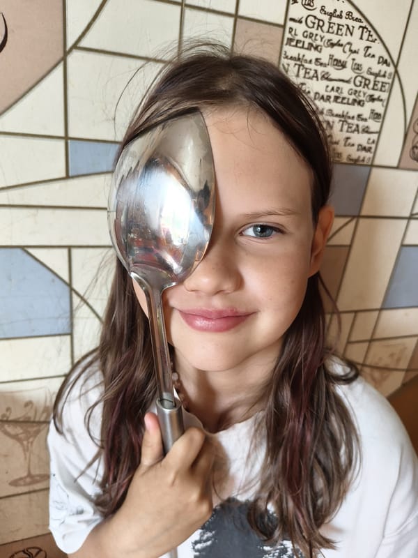 Playful eye-covering with spoon and grey tabby cat portraits