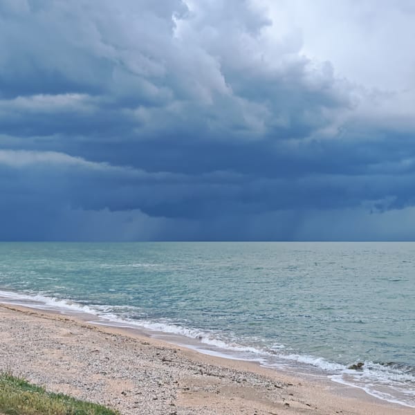 Dark storm clouds gather over tranquil beach waters