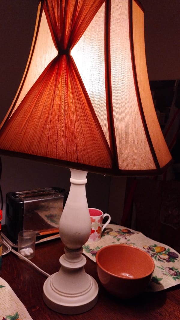 Cozy indoor table scene with lamp, ceramics, dolls, and a bird