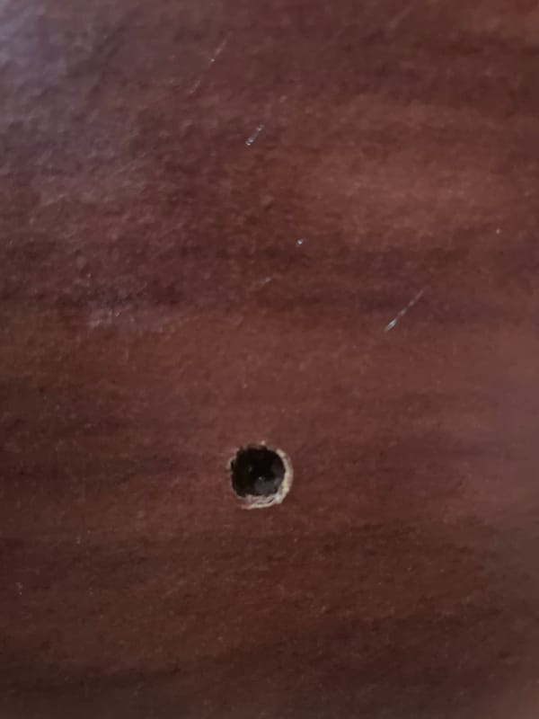 Close-up of a small hole in a textured wooden surface