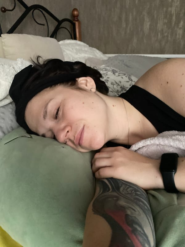 Person relaxes in bed with cat in Chaikovsky