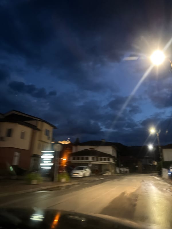 Dusk falls on a quiet Lovech street under stormy skies
