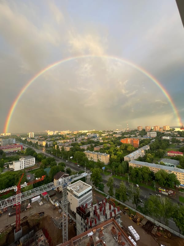 Double rainbow over a city construction site at dusk
