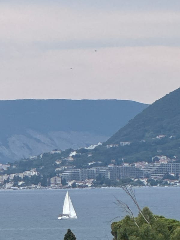 Coastal town nestled beneath green hills on a cloudy day