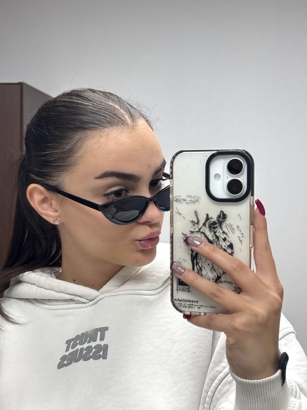 Woman takes selfie in white hoodie and sunglasses