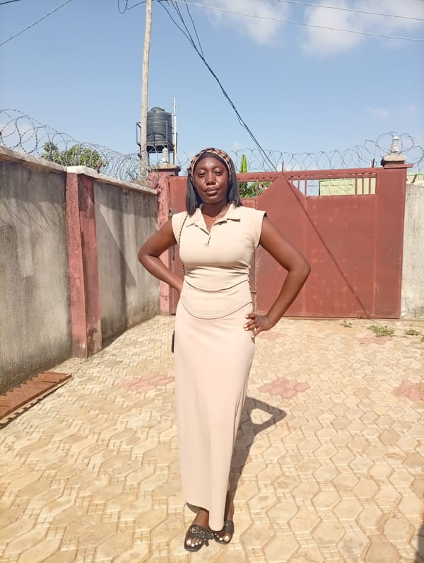 Woman in brown dress photographed near barbed wire barrier