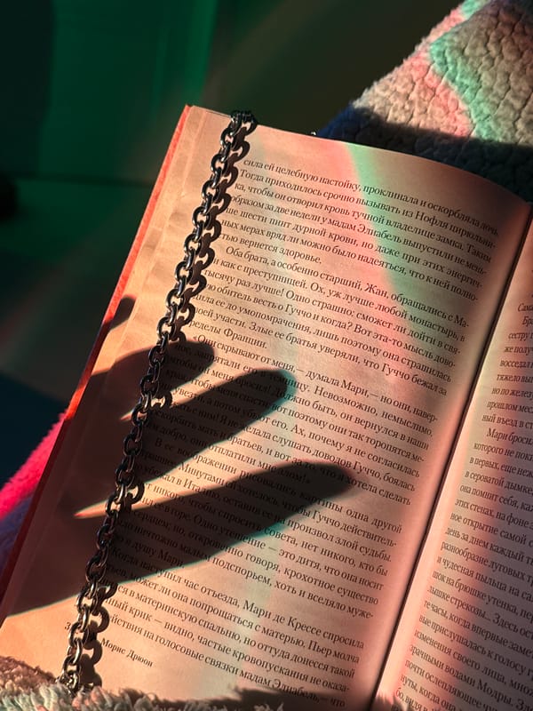 Person reads Russian book while arranging jewelry in bedroom