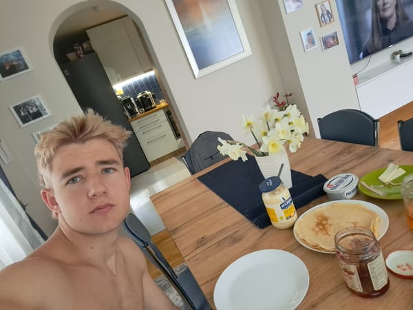Young man takes shirtless selfie at dining table in Sofia