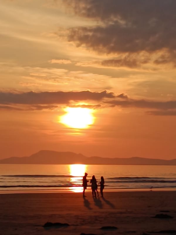 Beach scene at golden hour, people scattered along the shore