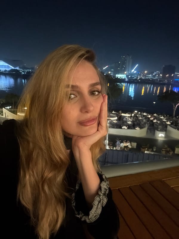 Woman dines at waterfront restaurant overlooking Dubai skyline