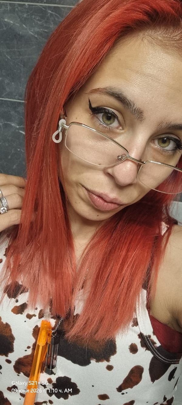 Red-haired woman takes indoor selfies wearing cow print top