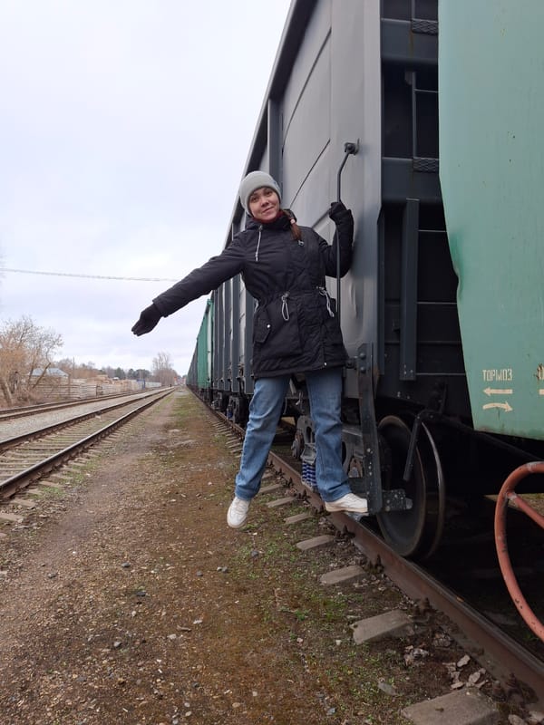 Person photographed lying against train car in rotated image