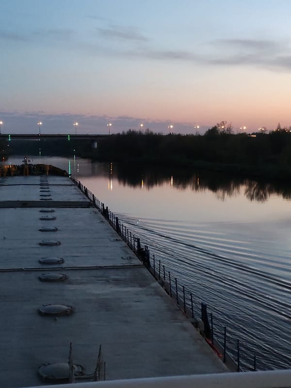 Barge navigates Dmitrov waterway at twilight