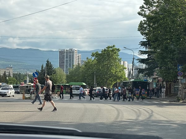 Tbilisi intersection buzzing with traffic and pedestrians on a cloudy morning