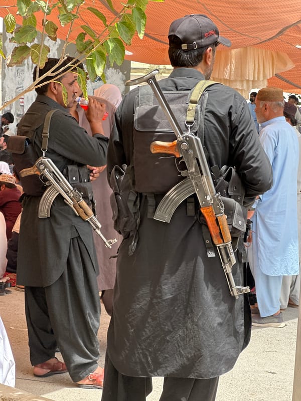 Armed figures and a seated gathering in Quetta, Pakistan