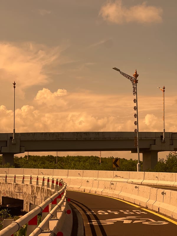 Motorcyclist takes selfies while crossing decorative bridge in Denpasar