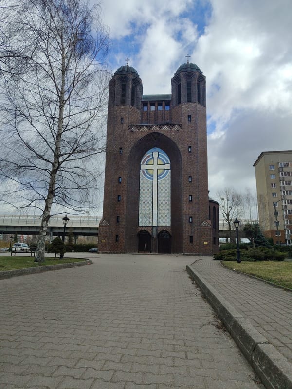 Twin-towered brick church with stained-glass cross window observed