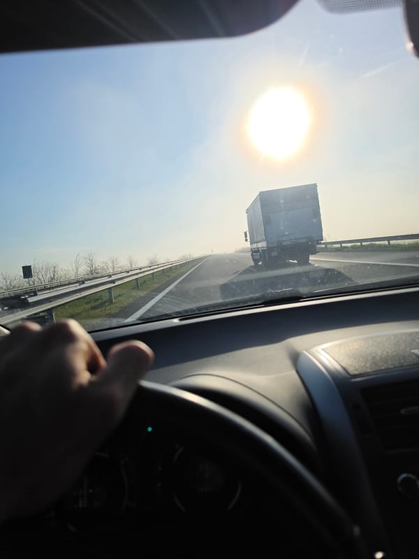 Morning highway drive captured with truck ahead, sunny skies