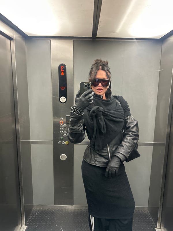 Person travels through London Underground wearing dark clothing, sunglasses
