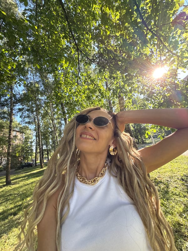 Woman in gold jewelry takes outdoor selfie