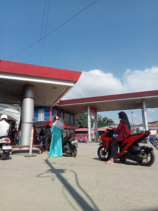 Morning scooter traffic at a rural Indonesian gas station