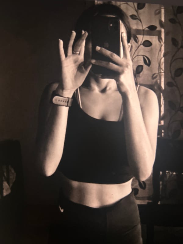 Woman in athletic wear photographs indoors with smartphone