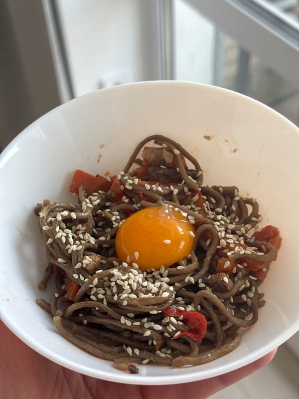 Person enjoys soba noodle breakfast with vegetables and egg