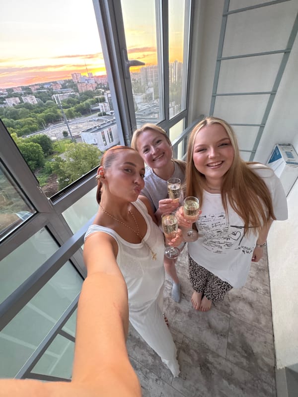 Women toast champagne at sunset overlooking Izhevsk cityscape