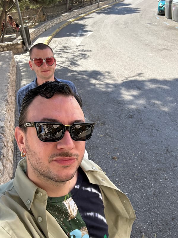 Men photographed near traditional green-shuttered buildings in Ibiza