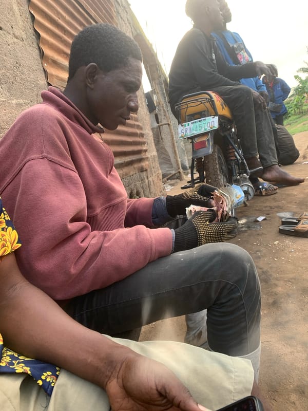 Roadside motorcycle repair and cash exchange in Shagamu, Nigeria