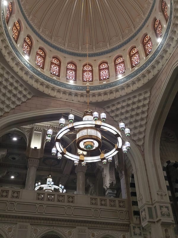 Mosque interior with ornate chandelier documented in Makkah
