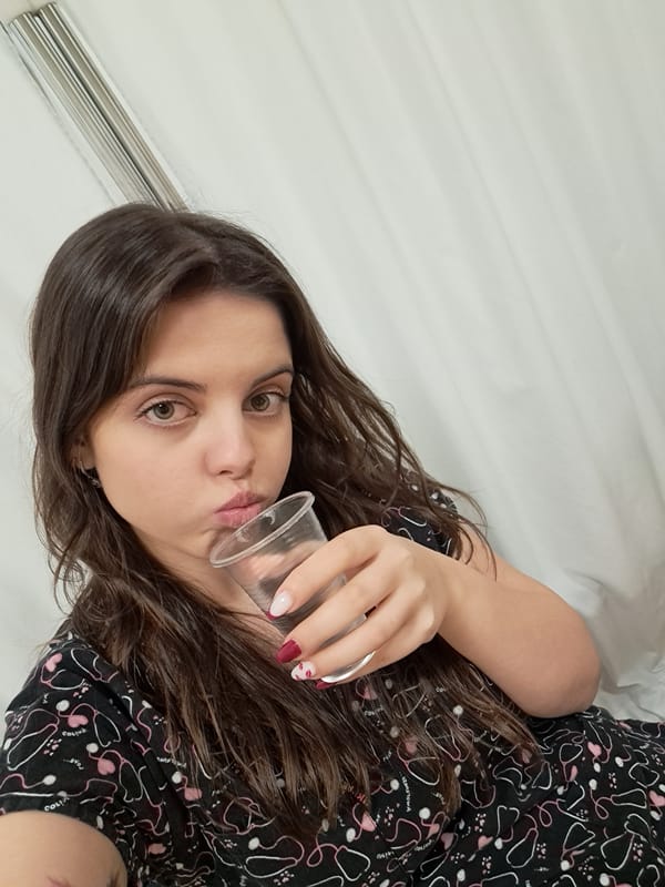 Woman in medical pajamas drinks from cup in Sofia