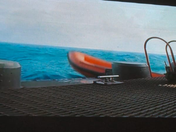 On a boat deck, railing and open water behind
