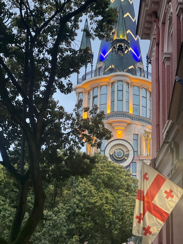 Batumi astronomical clock tower illuminated at night with Georgian flag