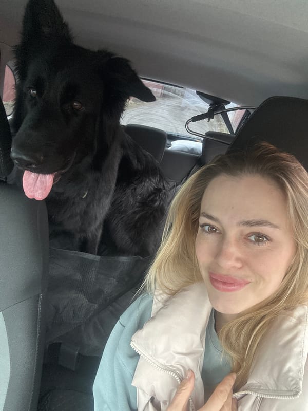 Woman takes car selfie with black dog