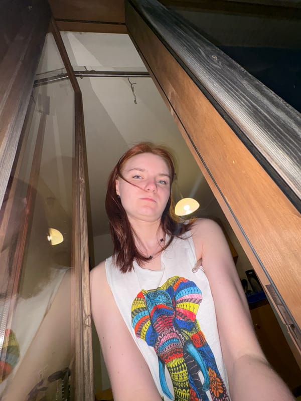 Red-haired person in white shirt photographed frowning at camera