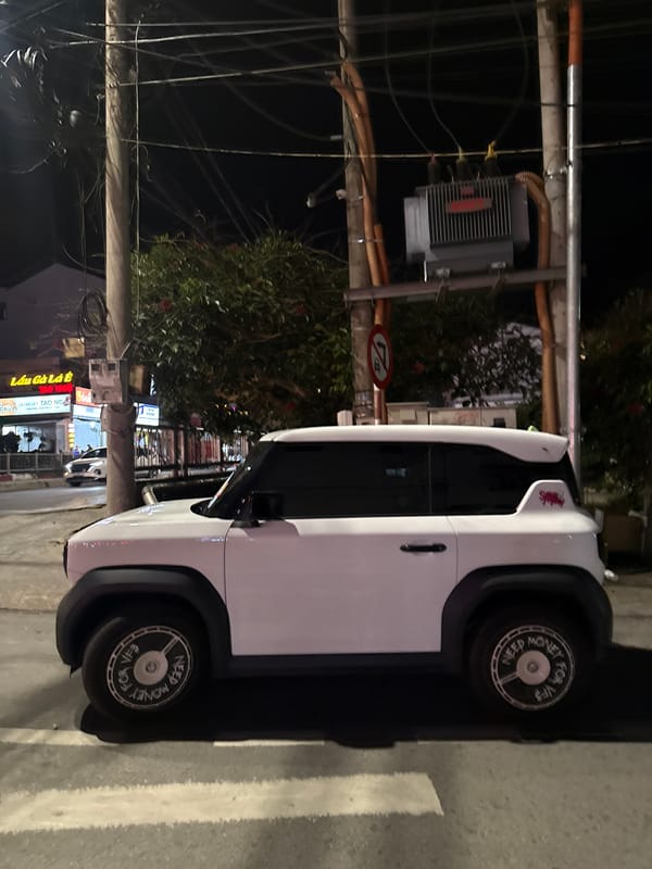 Modern electric car parked outside traditional Vietnamese building at night