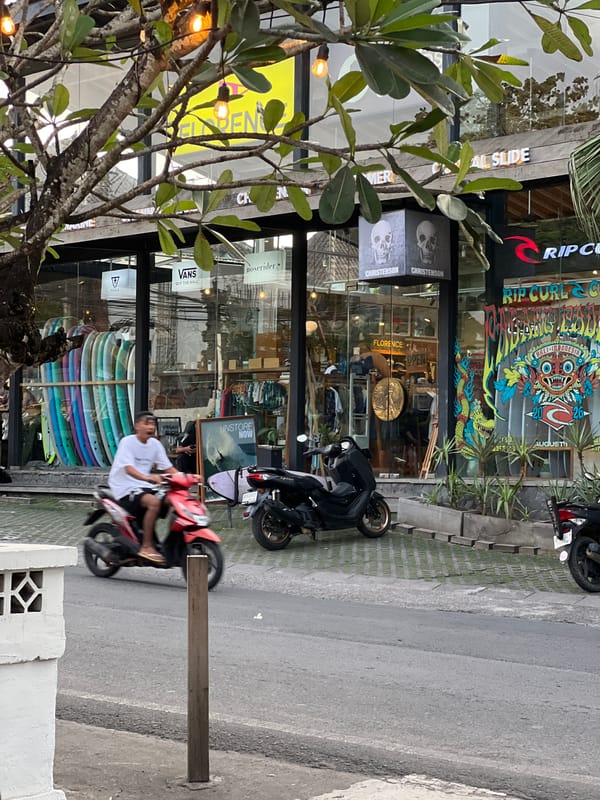 Surf shops and scooters along a busy Kuta Selatan street
