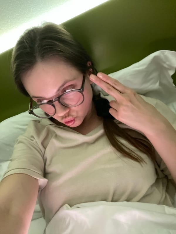 Woman makes peace sign while lying in bed in Venice