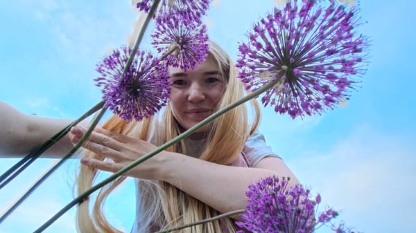 Woman poses with purple flowers during outdoor photoshoot in Russia