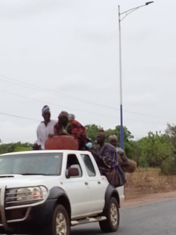 Pickup truck with roof passengers travels through Dungu, Ghana