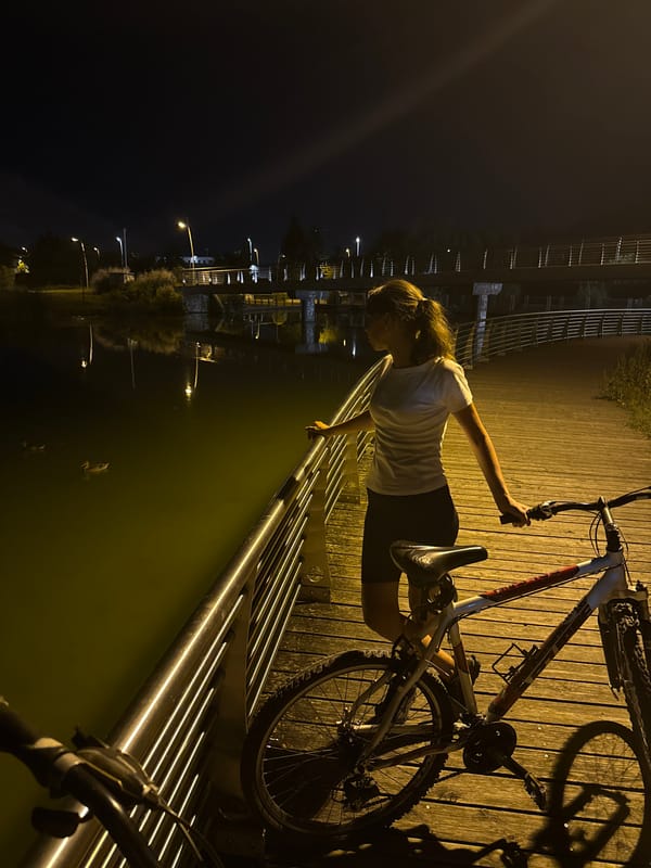 Night cycling along Trento's lit waterfront boardwalk